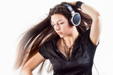 Büyük kulaklıklı genç esmer kadın müzik dinliyor ve eğleniyor..