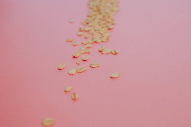 Eğlenceli sağlıklı gıda, kavram. Pembe bir arka plan üzerinde tahıl yulaf ezmesi. Yulaf gevreği dağınık