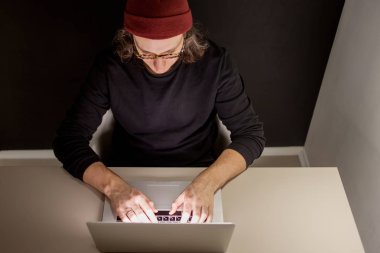 İşyerinde tasarımcı veya programcı. bir şapka ve gözlük bir dizüstü bilgisayarda oturan genç adam.