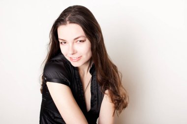 Genç, dost canlısı esmer gülümsüyor. Kendine güvenen genç bir kadının portresi.,