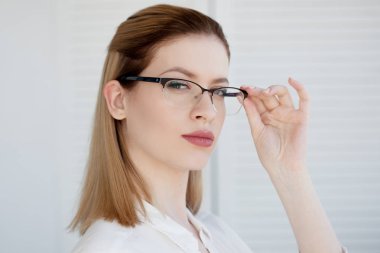 İnce çerçevede şık gözlükler, görme düzeltme. Genç bir kadının portresi