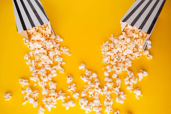 Popcorn in paper bag scattered on yellow background top view — Stock Photo, Image