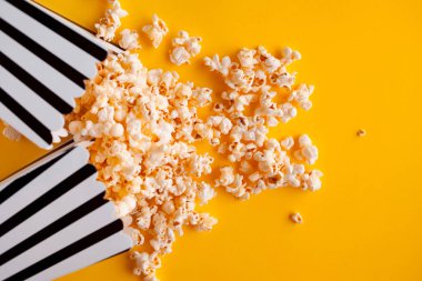 Sarı arka planda dağınık kağıt çanta Popcorn üst görünüm