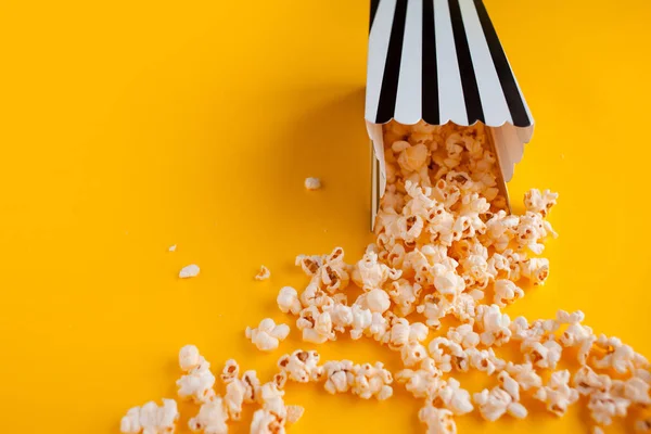 Popcorn in paper bag scattered on yellow background top view — Stock Photo, Image