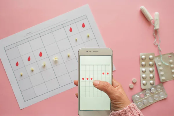 Adet döngüsü. Akıllı telefon ekranında işaretleri ve mobil uygulama ile ay için takvim.