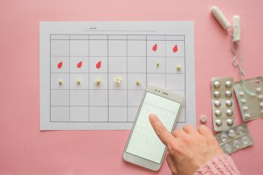 Adet döngüsü. Akıllı telefon ekranında işaretleri ve mobil uygulama ile ay için takvim.