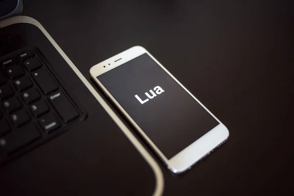 Programming language Lua for mobile development, concept. Smartphone near the laptop