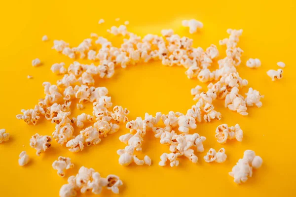 Delicious popcorn scattered on a yellow background — Stock Photo, Image