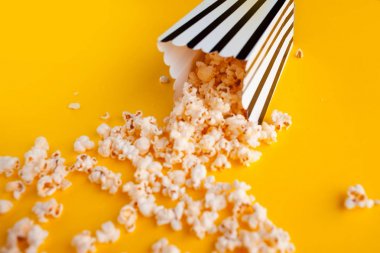 Sarı arka planda dağınık kağıt çanta Popcorn üst görünüm