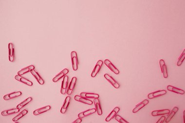 Dağınık pembe kağıt klipler. Pembe arka plan. Yatık.