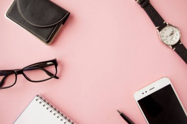 Kırtasiye, beyaz akıllı telefon, Gözlük, kalem, cüzdan, saat, takvim, defter. Pembe arka plan.