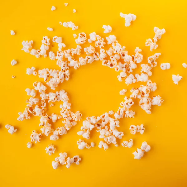 Delicious popcorn scattered on a yellow background — Stock Photo, Image