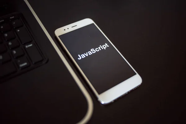 Programming language Javascript for mobile development, concept. Smartphone near the laptop