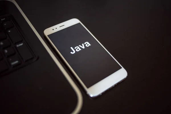Programmeringsspråk Java for mobilutvikling, konsept. Smarttelefon nær laptopen – stockfoto