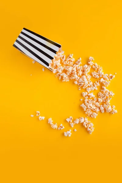 Popcorn in paper bag scattered on yellow background top view — Stock Photo, Image