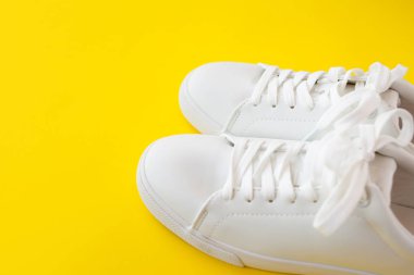 Mükemmel beyaz Yeni spor ayakkabıları parlak sarı bir arka plan üzerinde duruyor.