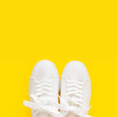 Mükemmel beyaz Yeni spor ayakkabıları parlak sarı bir arka plan üzerinde duruyor.