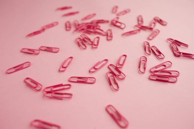 Dağınık pembe kağıt klipler. Pembe arka plan. Yatık.