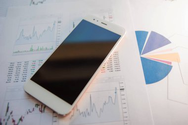 Menkul Kıymetler, konsept yatırım. Yatırımcıları için mobil uygulamalar. Finansal raporların arka planında Smartphone
