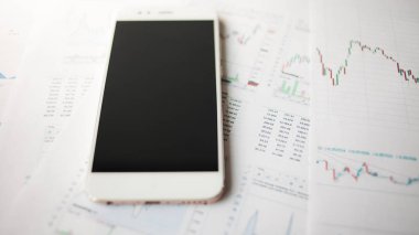 Menkul Kıymetler, konsept yatırım. Yatırımcıları için mobil uygulamalar. Finansal raporların arka planında Smartphone