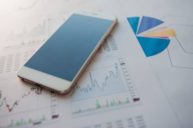 Finansal raporların arka planında boş ekrana sahip akıllı telefon