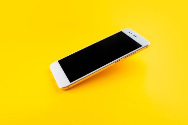 akıllı telefon bir açıyla yüzey üzerinde uçuyor, sarı bir arka plan,