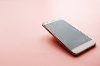 akıllı telefon bir açıyla yüzey üzerinde uçuyor, pembe bir arka plan,