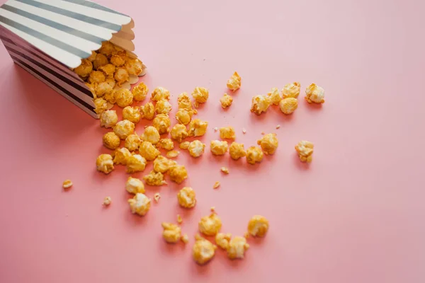 Popcorn in paper bag scattered on pink background top view — Stock Photo, Image
