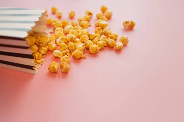 Popcorn in paper bag scattered on pink background top view — Stock Photo, Image