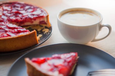 Hala bir fincan kahve ve çilek ile tatlı tatlı ile hayat, üst jöle içinde çilek dilimleri ile cheesecake kek.