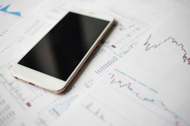 Menkul Kıymetler, konsept yatırım. Yatırımcıları için mobil uygulamalar. Finansal raporların arka planında Smartphone