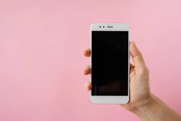 Akıllı telefon elinde, boş ekran pembe arka planda alay.