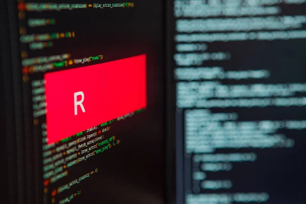 Programmeringsspråk, R inskription på bakgrunden av datorkod. — Stockfoto