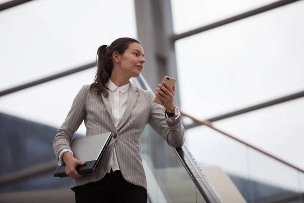 Young businesswoman with glasses and a phone in her hands. In the office or business center.