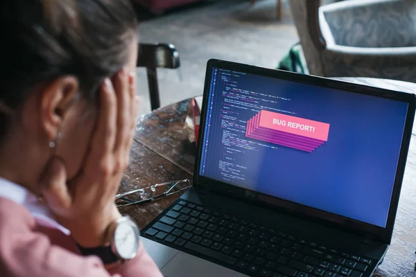 Er ging iets mis. Zeer opgewonden meisje in de voorkant van de laptop, met sitecode op display is gesloten met rode fout waarschuwing. — Stockfoto