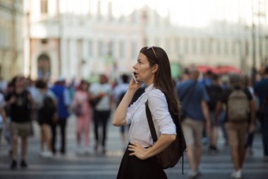 Büyük şehrin sokaklarında kalabalığın içinde olan kız. Şehirde genç bir kadın cep telefonu kullanıyor.
