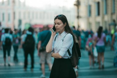 Büyük şehrin sokaklarında kalabalığın içinde olan kız. Şehirde genç bir kadın cep telefonu kullanıyor.