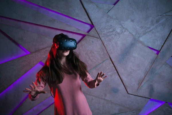 Watch out. Young woman with vr glasses and fluttering hair actively reacts, is afraid of what is happening in the game.