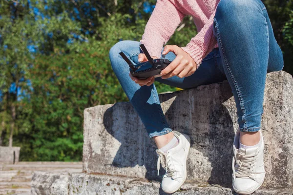 Pembe kapüşonlu genç bir kadın taş bir bankta oturan ve uzaktan kumandalı drone uçuş tarafından işletilen. — Stok fotoğraf