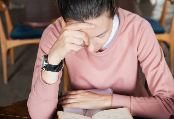 Manque de sommeil. Étudiante, brune, penchée sur des livres à une table dans une vieille bibliothèque, soutenant sa tête avec sa main . — Photo