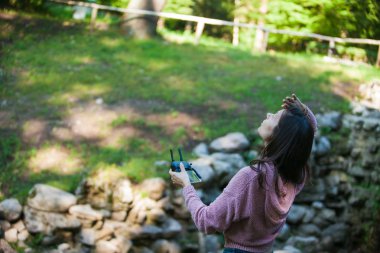 Her şey kontrol altında. Drone kontrol paneli ile ormanda kadın başının üstünde havada bir şey için dışarı bakar.