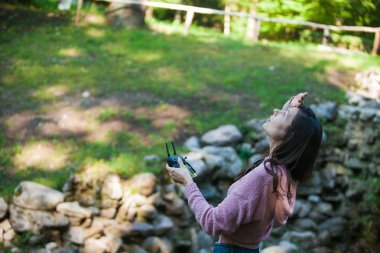 Her şey kontrol altında. Drone kontrol paneli ile ormanda kadın başının üstünde havada bir şey için dışarı bakar.