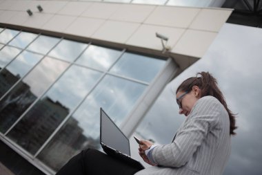 İş merkezinin arka planda elinde bir dizüstü bilgisayar ile genç hırslı kadın.