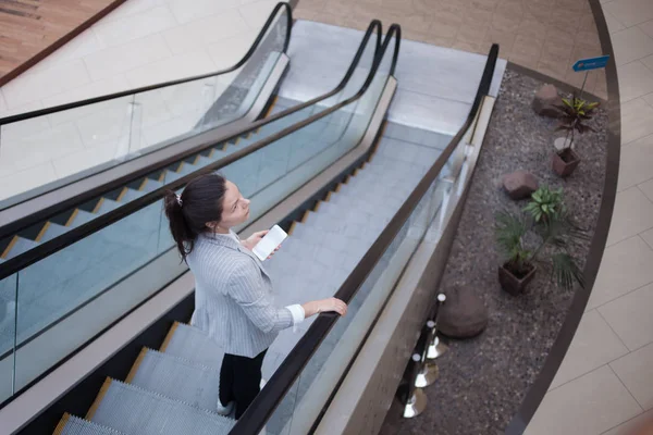 Young businesswoman on the escalator and a phone in her hands. In the office or business center.