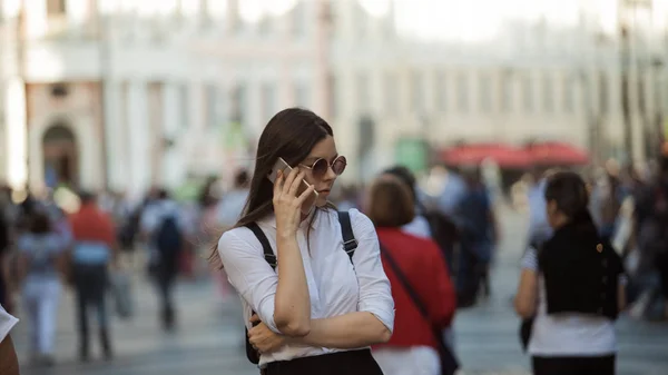 Das Mädchen in der Menschenmenge auf den Straßen der Großstadt. Eine junge Frau in der Stadt benutzt ein Handy — Stockfoto