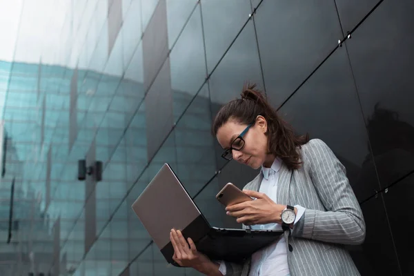 Career growth and ambitions, concept. Young businesswoman with a laptop in her hands on the background of the business center.