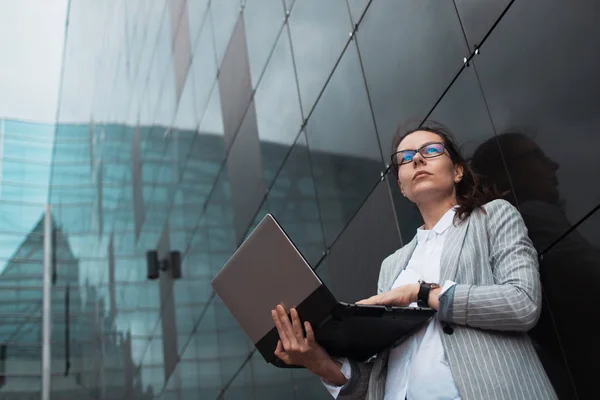 Карьерный рост и амбиции, концепция. Молодая деловая женщина с ноутбуком в руках на фоне бизнес-центра . — стоковое фото