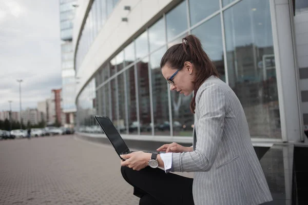 Карьерный рост и амбиции, концепция. Молодая деловая женщина с ноутбуком в руках на фоне бизнеса  . — стоковое фото
