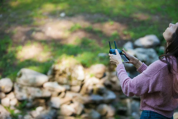 Everything\'s under control. Woman in forest with drone control panel looks out for something in the air above her head.