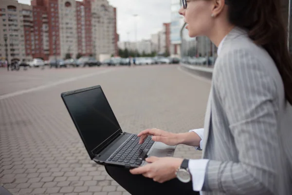 Career growth and ambitions, concept. Young businesswoman with a laptop in her hands on the background of the business .